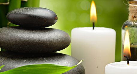 Stacked basalt stones next to lit white candles
