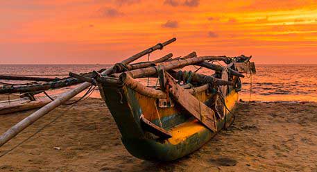 A traditional boat on the shore during sunset