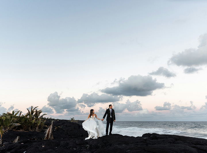 A bride and groom walking near the sea