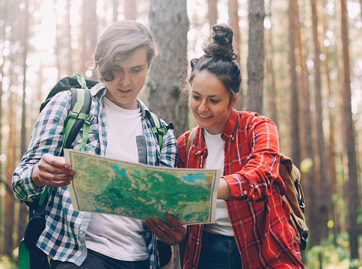 Two people looking at a map in a forest